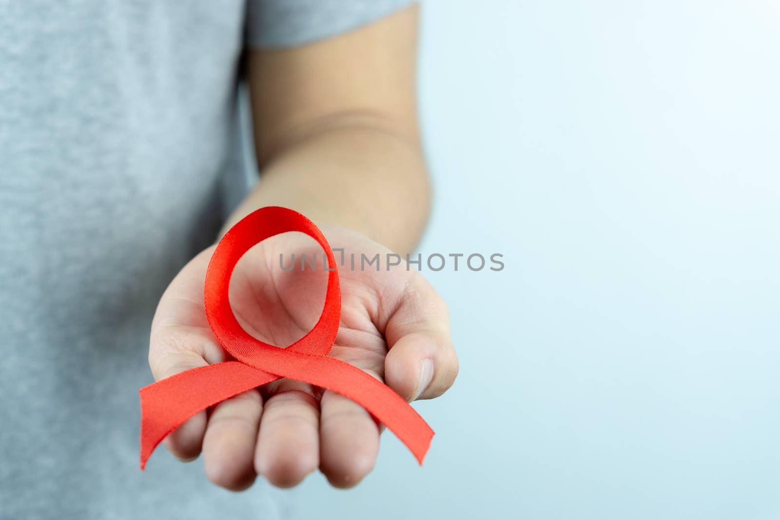 Aids awareness, male hands holding red AIDS awareness ribbon. Wo by mikesaran