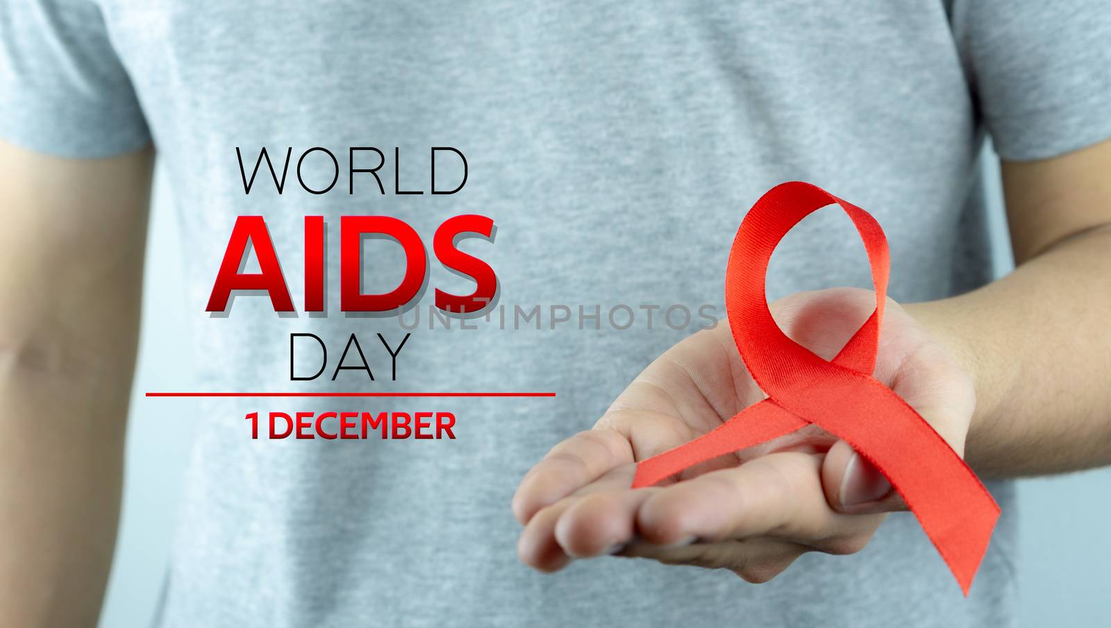 Aids awareness, male hands holding red AIDS awareness ribbon. Wo by mikesaran