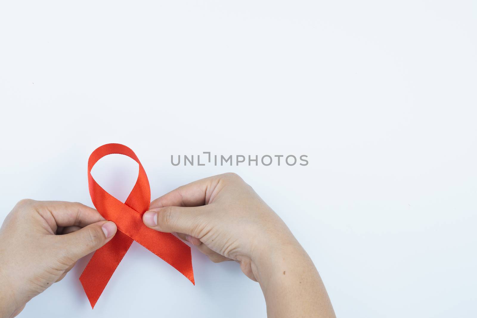 Aids awareness, male hands holding red AIDS awareness ribbon on  by mikesaran