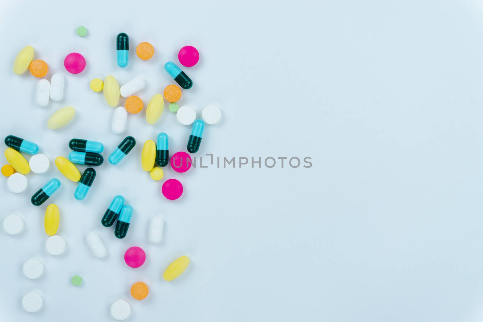 Assorted pharmaceutical medicine pills, tablets and capsules, and bottle on white background. Copy space for text, top view.