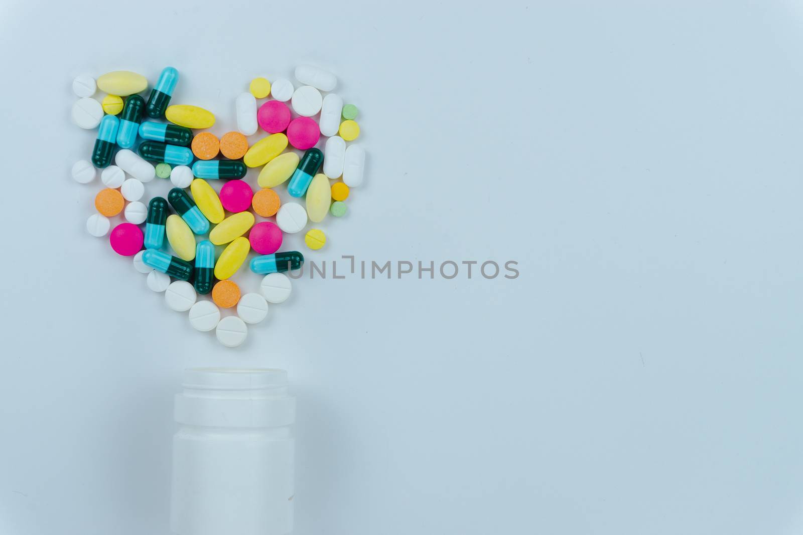 Assorted pharmaceutical medicine pills, tablets and capsules, and bottle on white background. Copy space for text, top view.