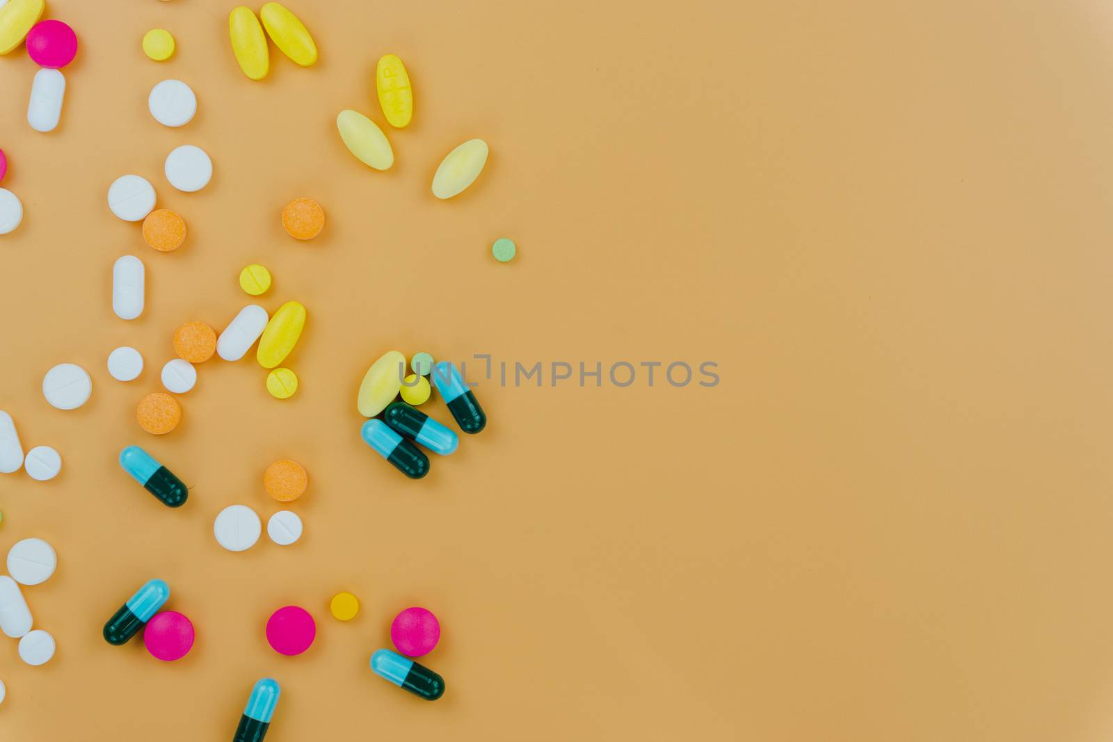 Assorted pharmaceutical medicine pills, tablets and capsules, and bottle on yellow background. Copy space for text, top view.