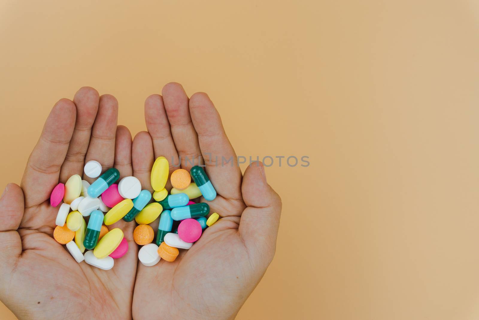 Top view of woman hands holding assorted pharmaceutical medicine pills on yellow background. Hard working and stressful business work overtime, health care concept.