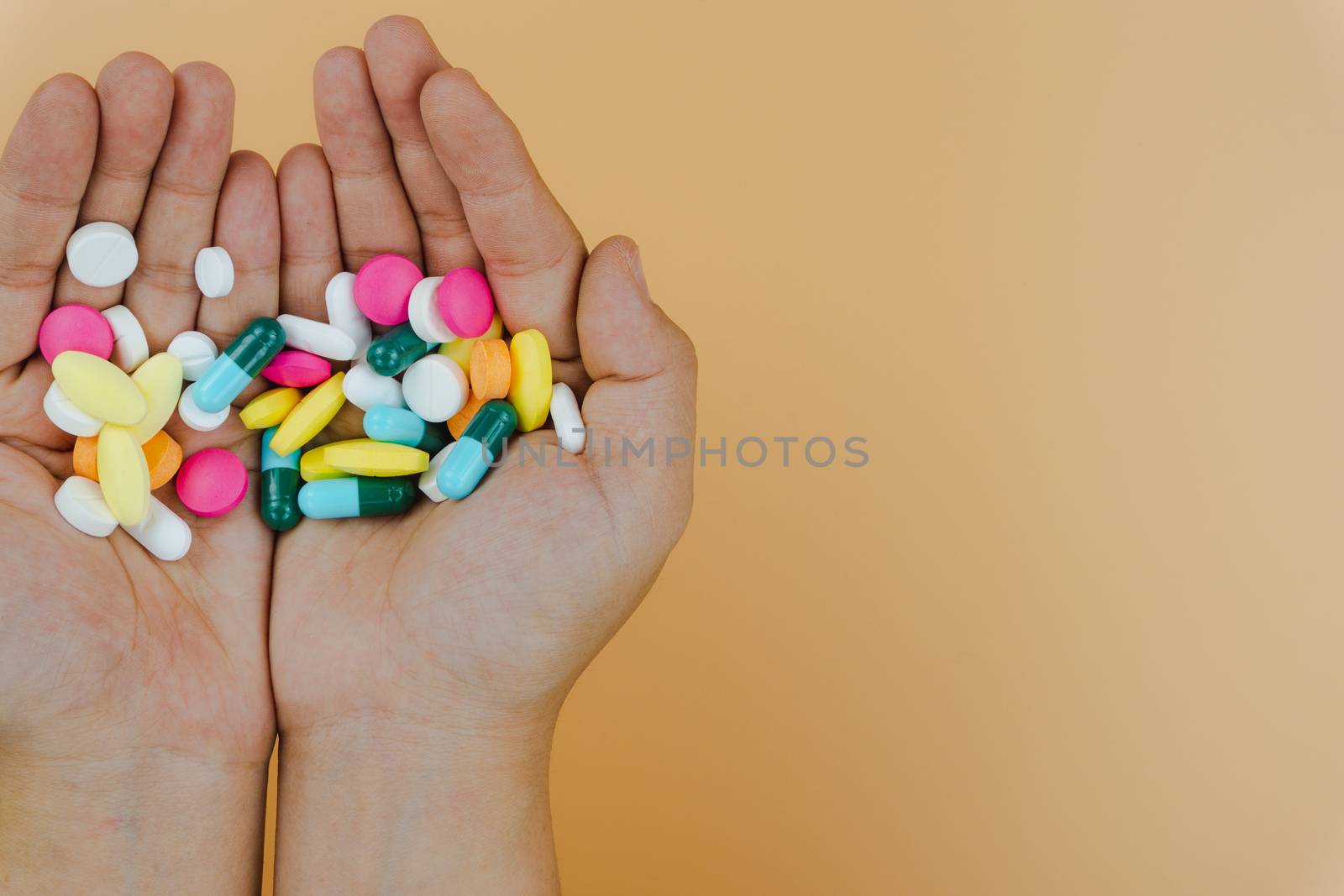 Top view of woman hands holding assorted pharmaceutical medicine pills on yellow background. Hard working and stressful business work overtime, health care concept.