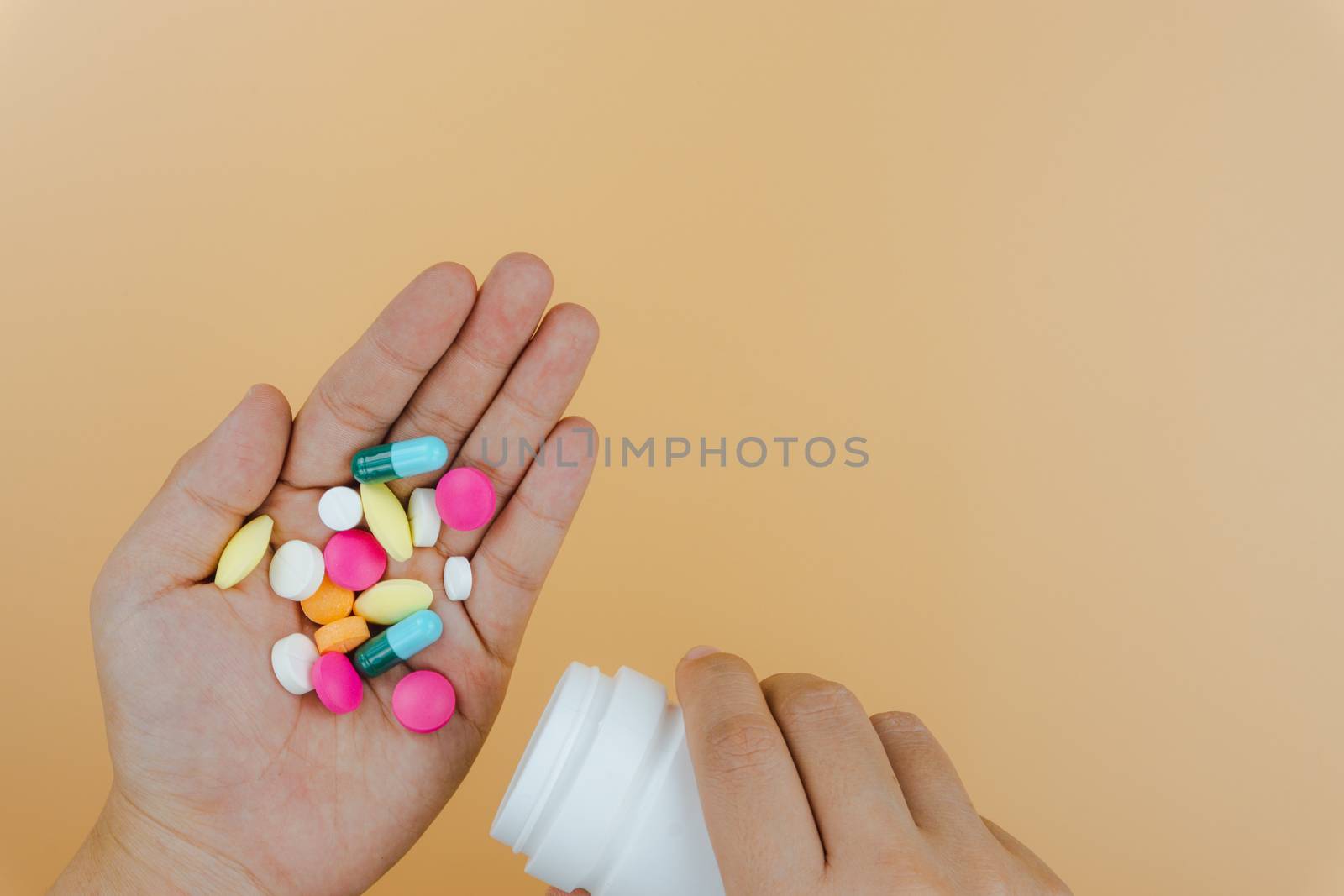 Top view of woman hands holding white bottle pill to taking medication on yellow background. Hard working and stressful business work overtime, health care concept.