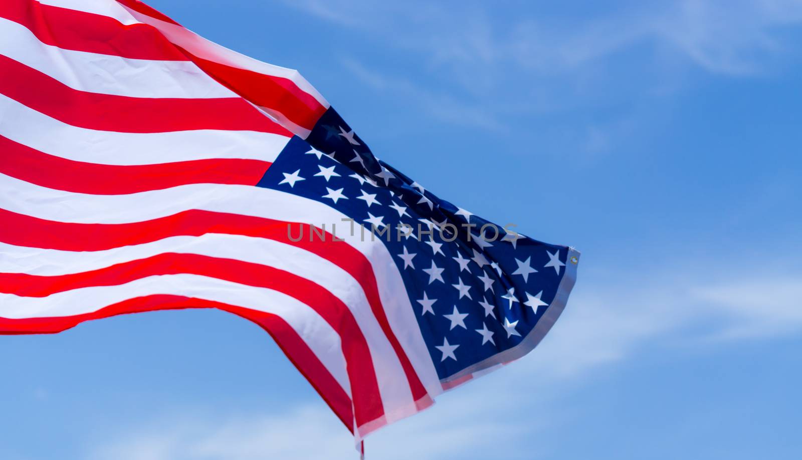 US American flag on blue sky background. For USA Memorial day, Veterans day, Labor day, or 4th of July celebration. Top view, copy space for text.