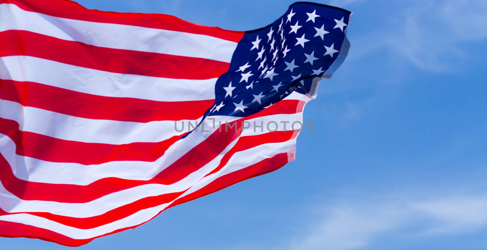 US American flag on blue sky background. For USA Memorial day, Veterans day, Labor day, or 4th of July celebration. Top view, copy space for text.