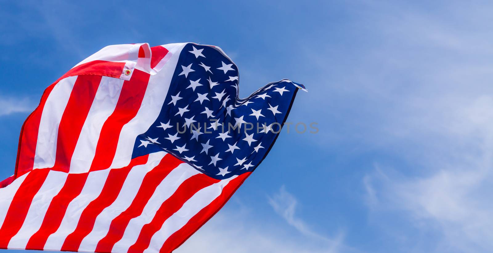 US American flag on blue sky background. For USA Memorial day, Veterans day, Labor day, or 4th of July celebration. Top view, copy space for text.