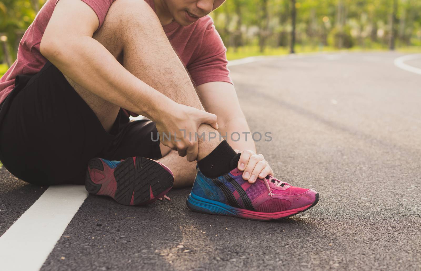 Ankle sprained. Young man suffering from an ankle injury while running at park. Healthcare and sport concept.