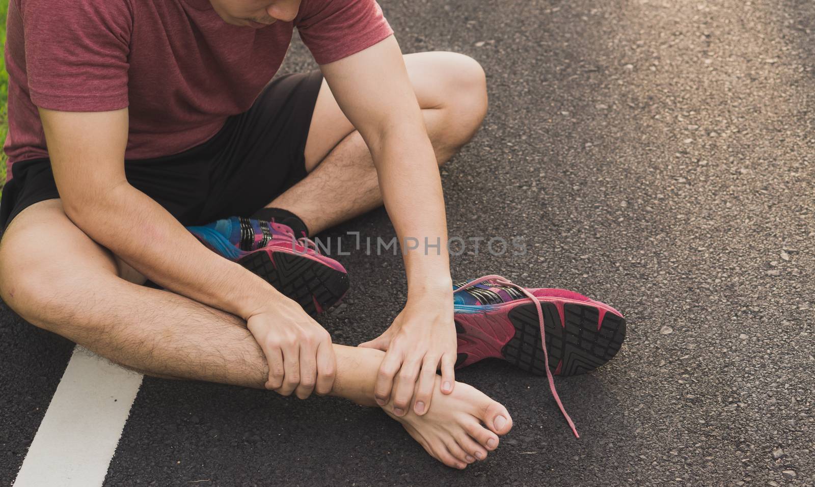 Ankle sprained. Young man suffering from an ankle injury while running at park. Healthcare and sport concept.