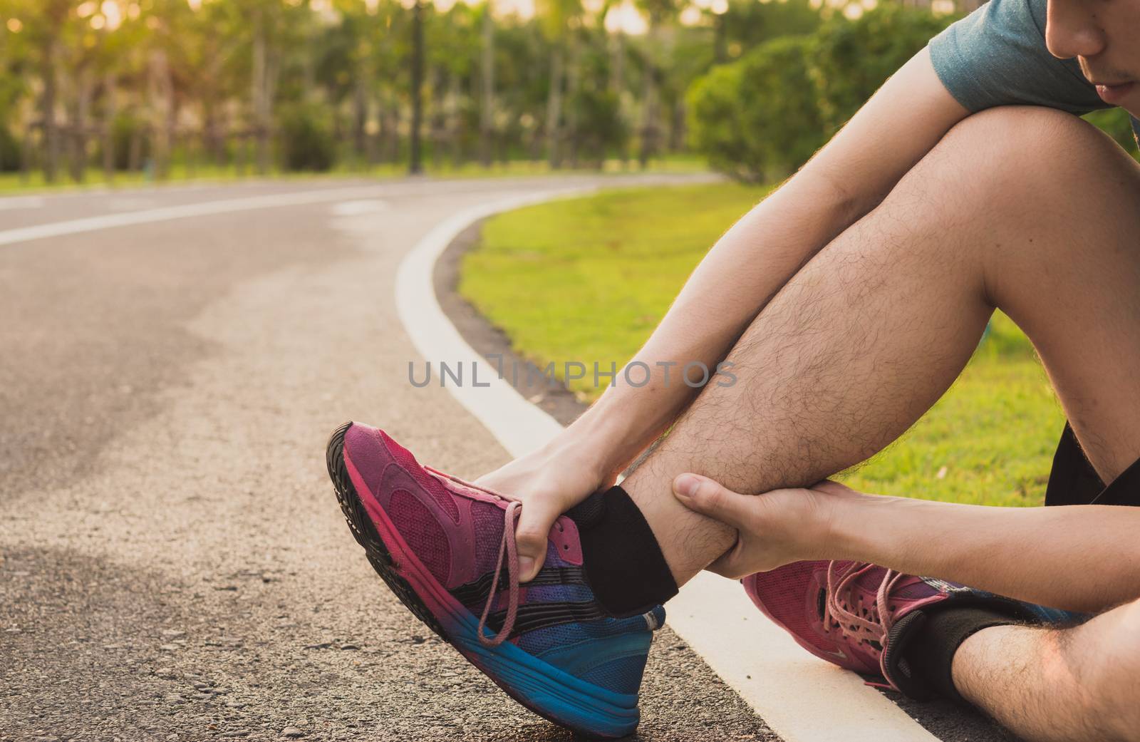 Ankle sprained. Young man suffering from an ankle injury while running at park. Healthcare and sport concept.