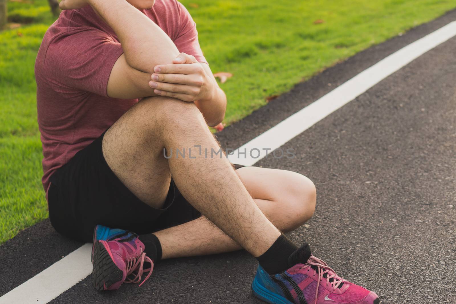 A male athlete suffering from arm and elbow pain and injury at the park. Sport and healthcare concept.