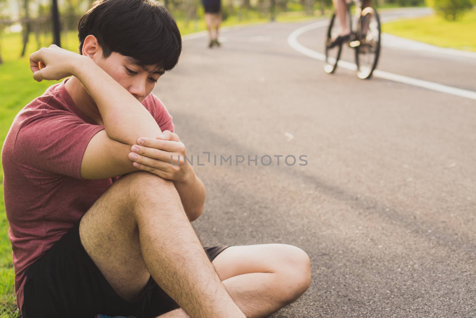 A male athlete suffering from arm and elbow pain and injury at the park. Sport and healthcare concept.