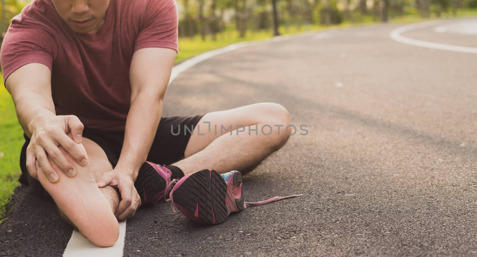 Young man massaging his painful foot from jogging and running on by mikesaran