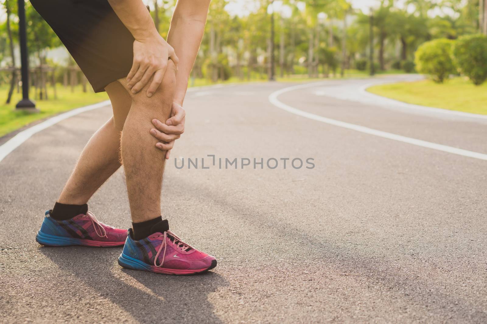 Knee Injuries. Young sport man holding knee with his hands in pa by mikesaran