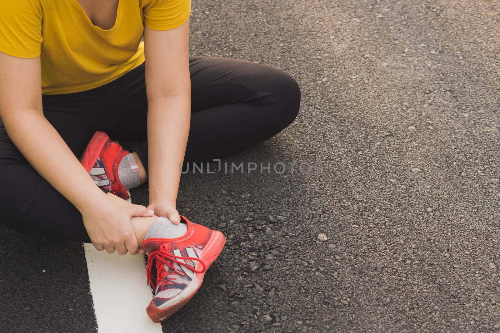 Ankle sprained. Young woman suffering from an ankle injury while jogging and running at the park. Healthcare and sport concept.