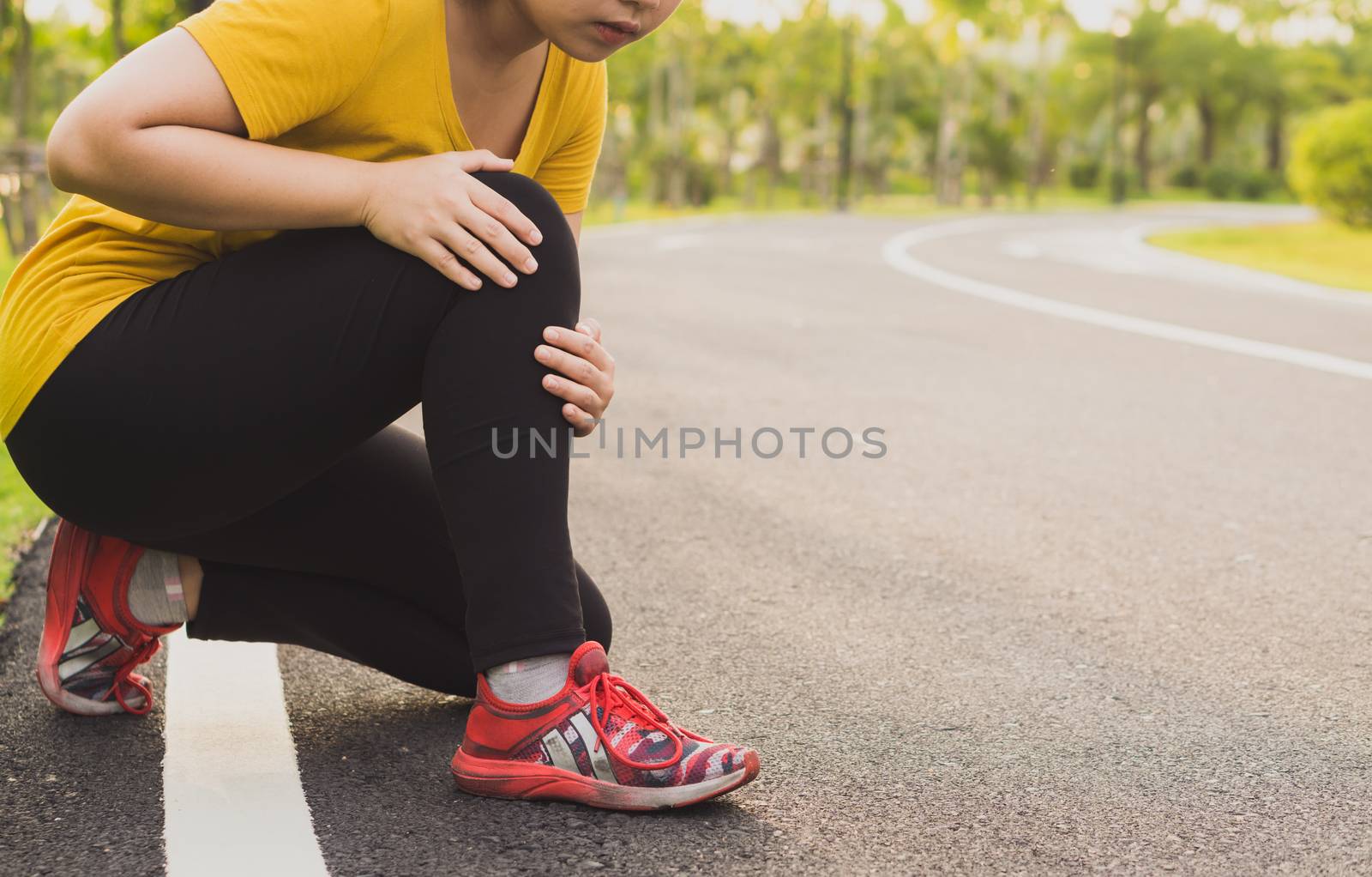 Knee Injuries. Young sport woman holding knee with her hands in pain after suffering muscle injury during a running workout at the park. Healthcare and sport concept.