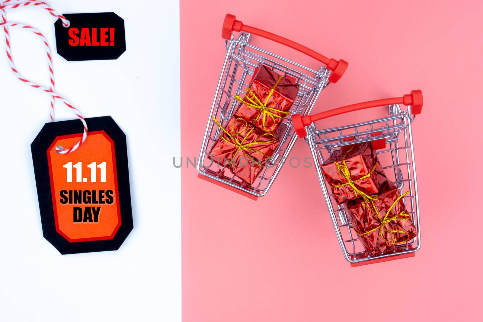 Online shopping of China, The shopping cart and Christmas boxes with red ribbon and shopping tag on a pink and white background with copy space for text. 11.11 single's day sale concept