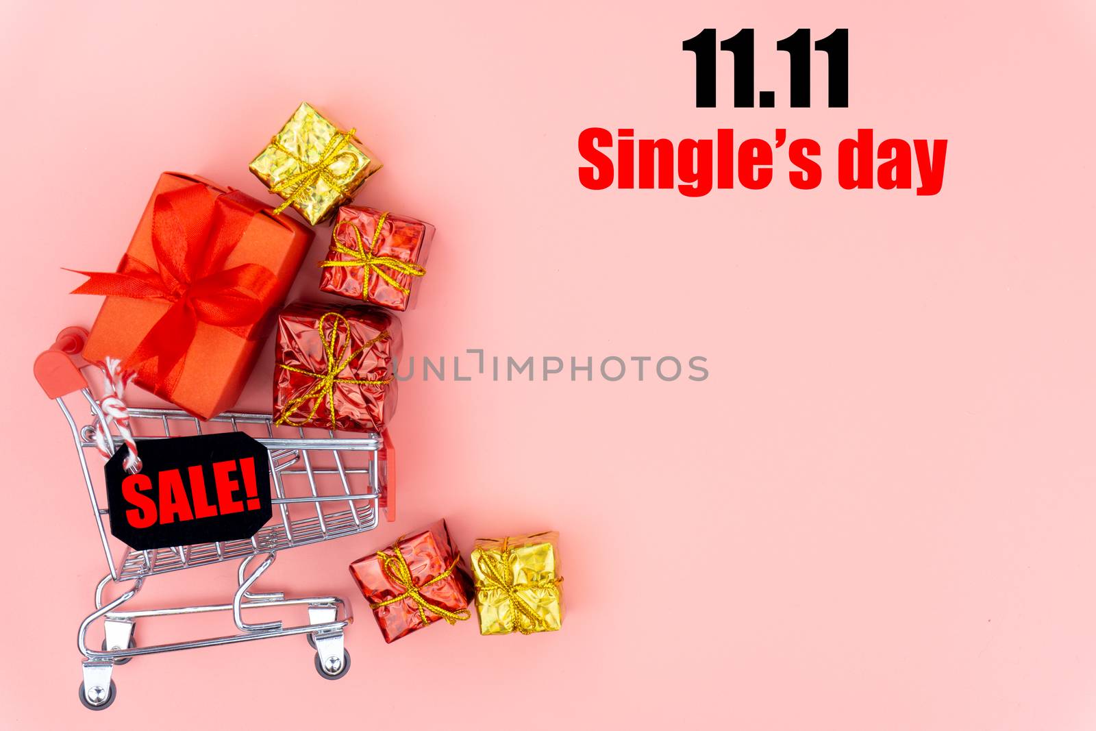 The shopping cart and Christmas boxes with red ribbon on a pink background with copy space for text.Online shopping of China, 11.11 single's day sale concept