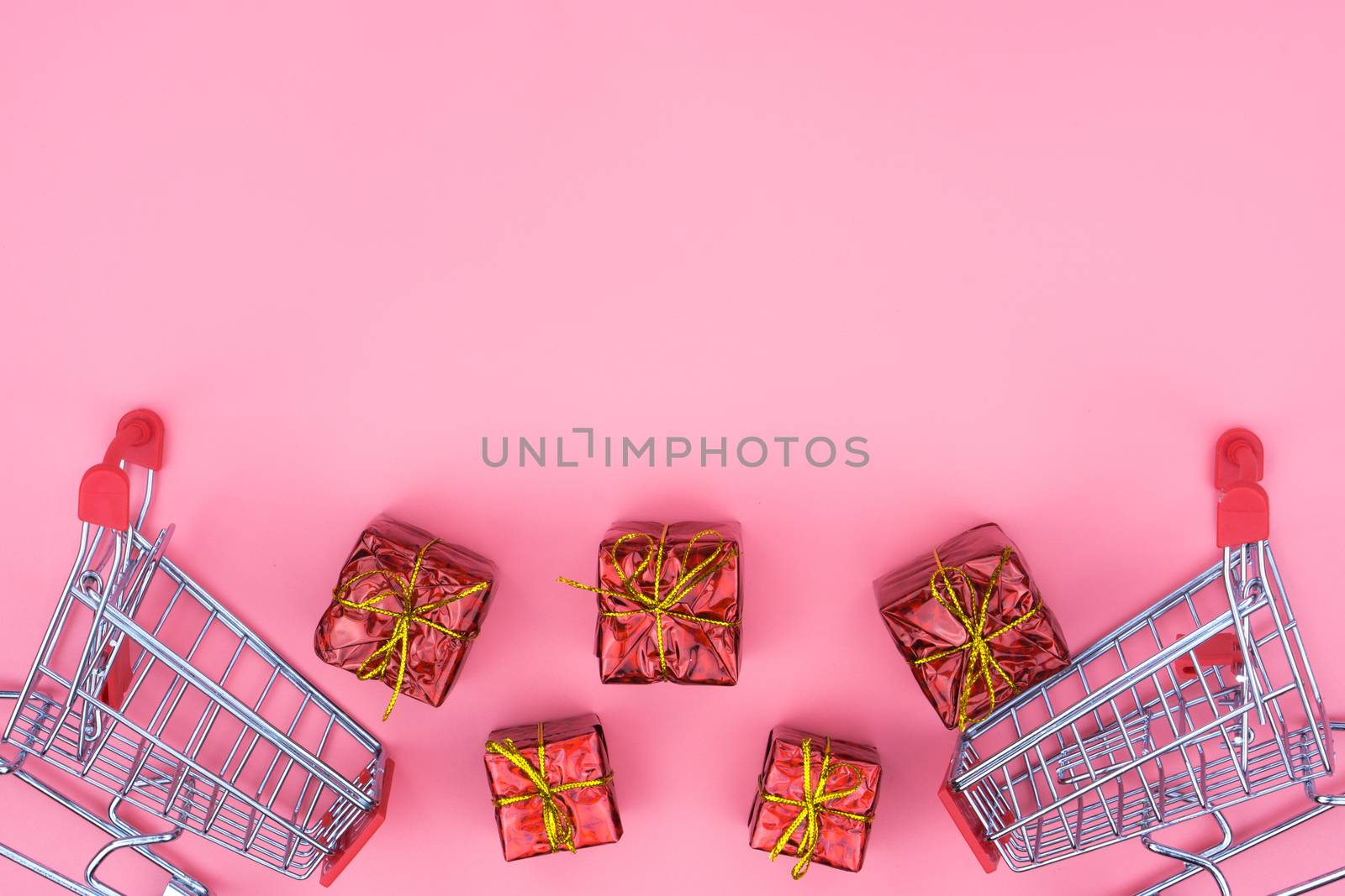 Online shopping of China, The shopping cart and Christmas boxes with red ribbon on a pink background with copy space for text. 11.11 single's day sale concept