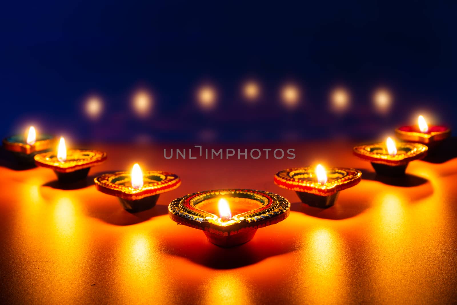 Indian festival Diwali, Diya oil lamps lit on colorful rangoli.  by mikesaran