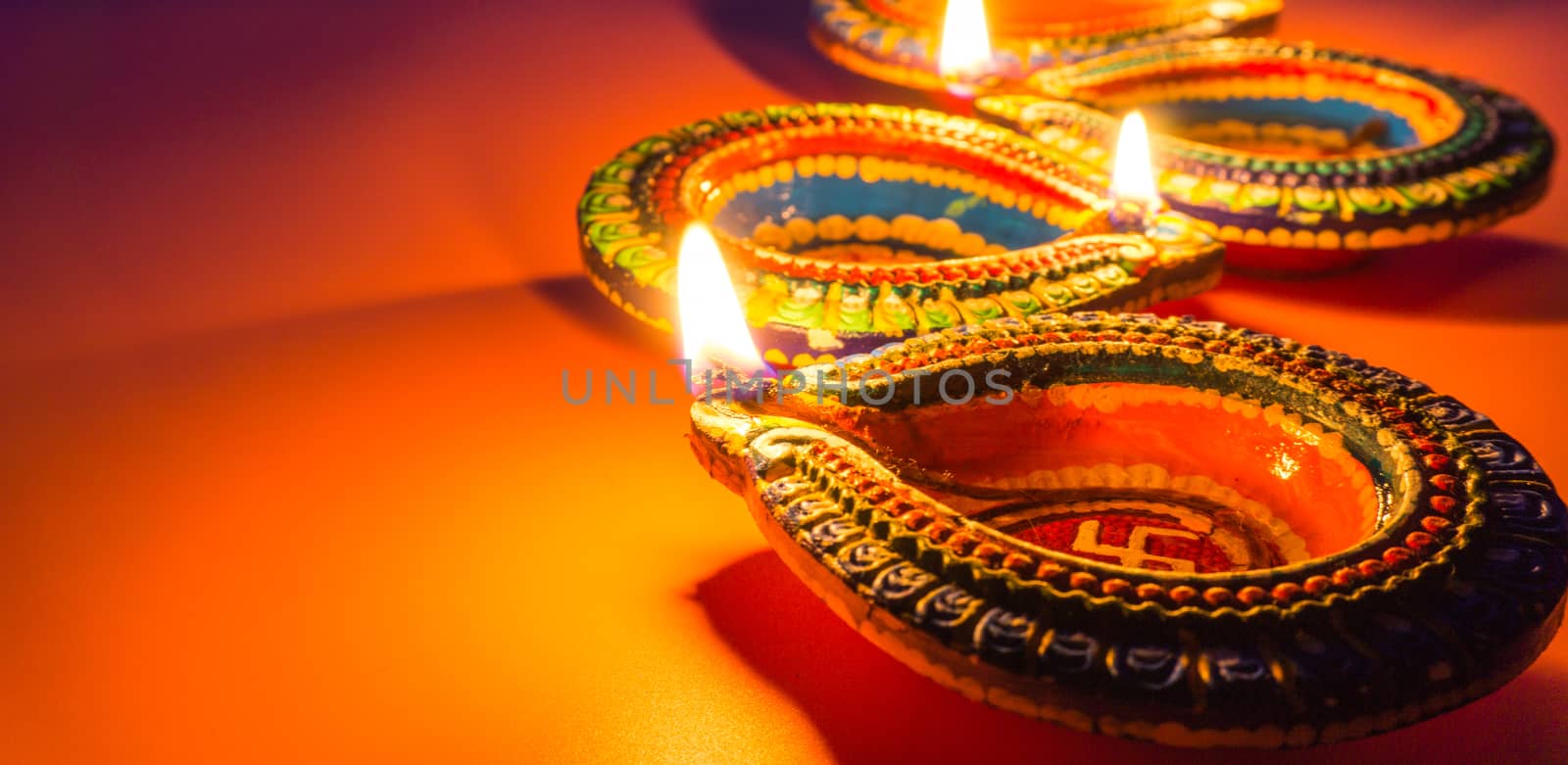 Indian festival Diwali, Diya oil lamps lit on colorful rangoli. Hindu traditional. Happy Deepavali. Copy space for text.