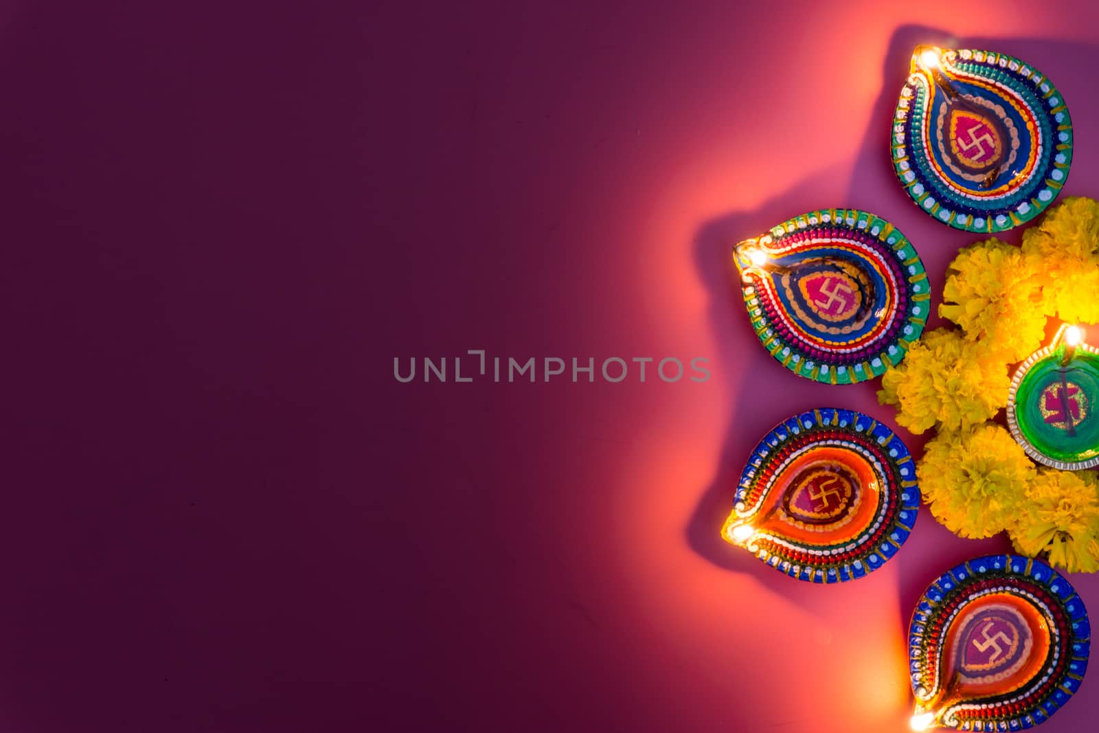 Indian festival Diwali, Diya oil lamps lit on colorful rangoli.  by mikesaran