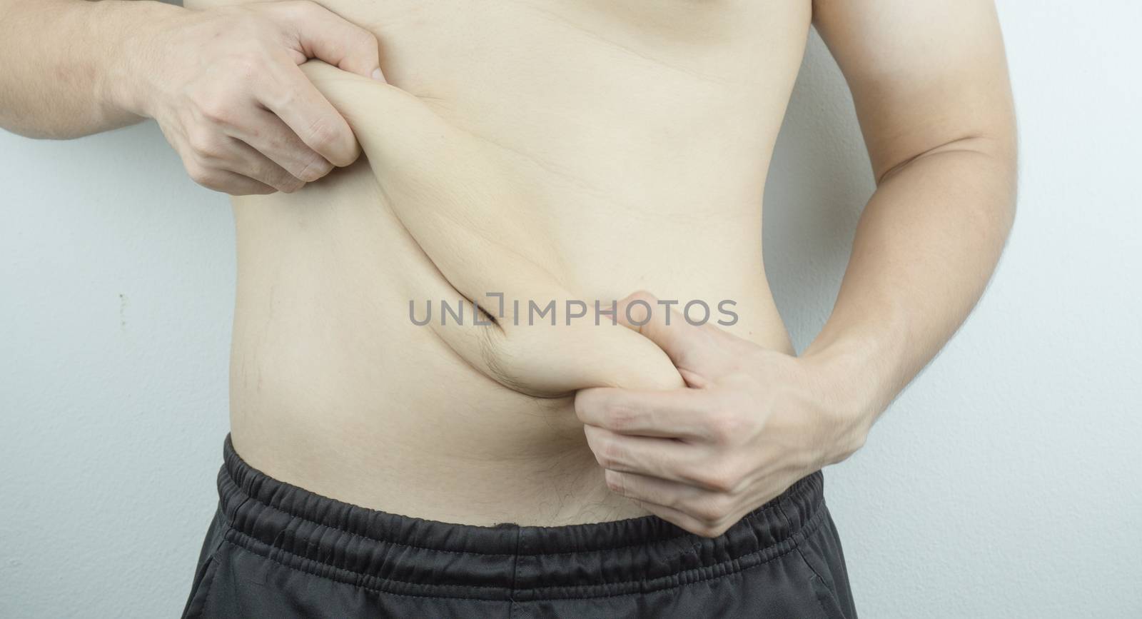 Close up man holding excessive fat belly on white background. Di by mikesaran