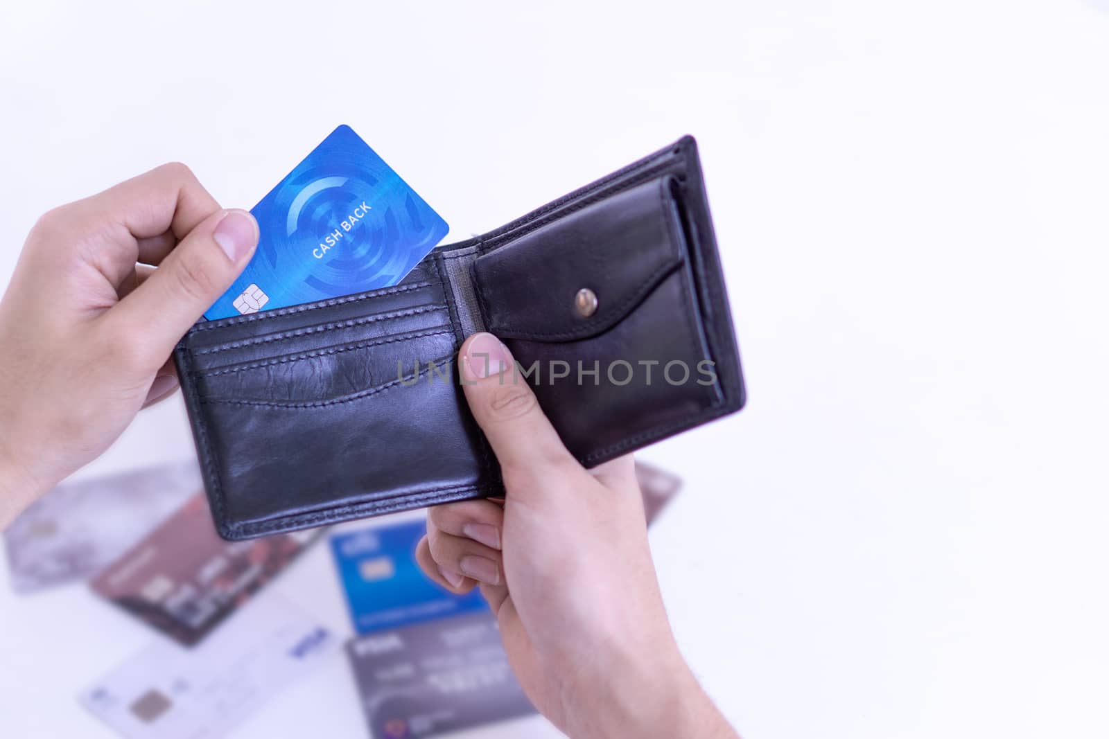 Man hand taking out the credit card for payment from the black leather wallet with many credit card on the white table.  Finance and money concept, copy space for text.