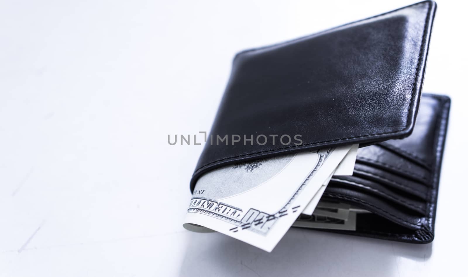 A black leather wallet with money inside on the white table. Mon by mikesaran