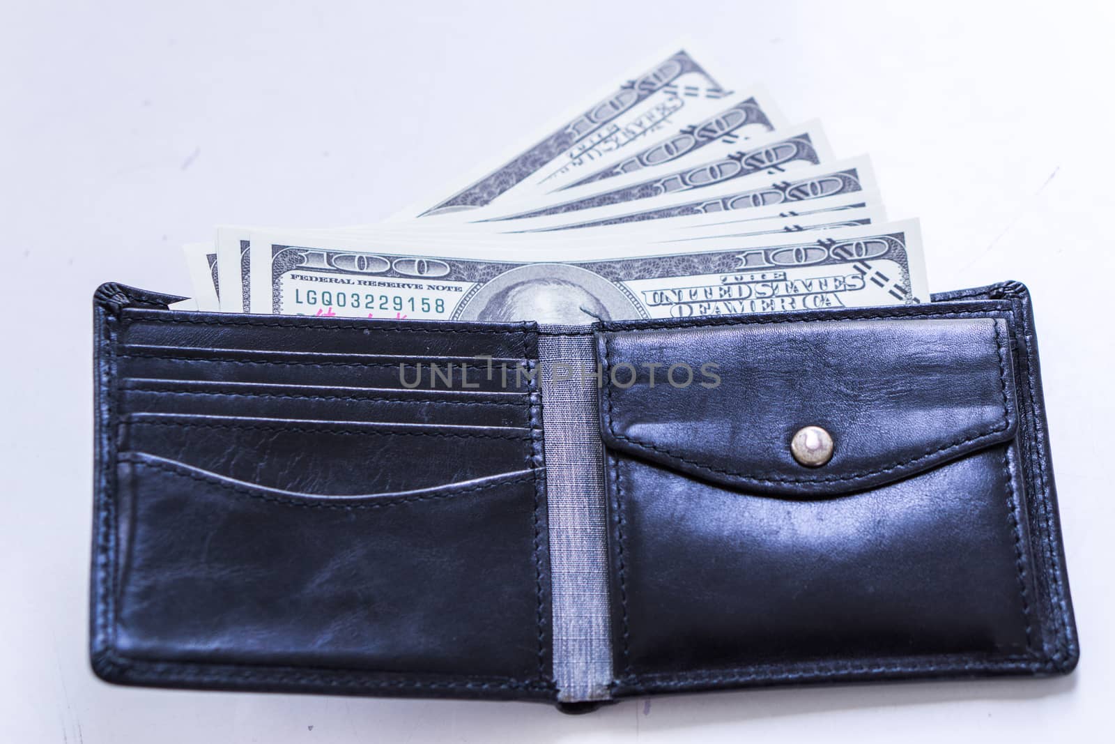 A black leather wallet with money inside on the white table. Money concept, copy space for text.