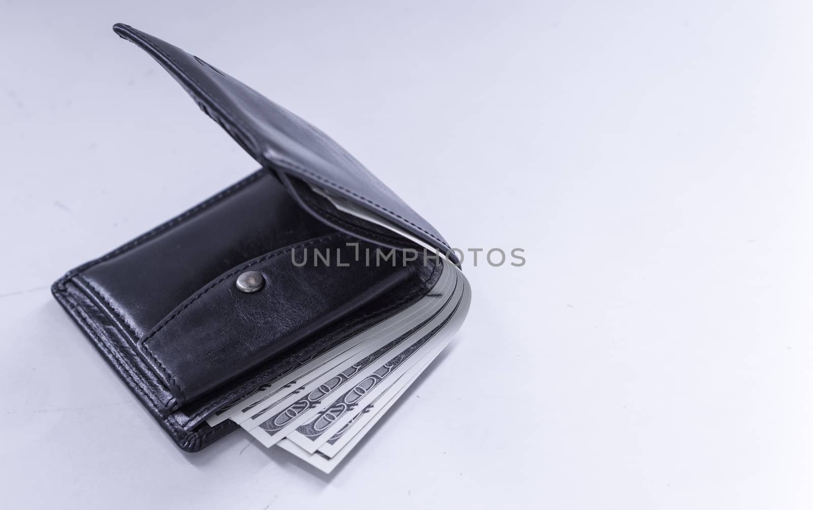 A black leather wallet with money inside on the white table. Mon by mikesaran