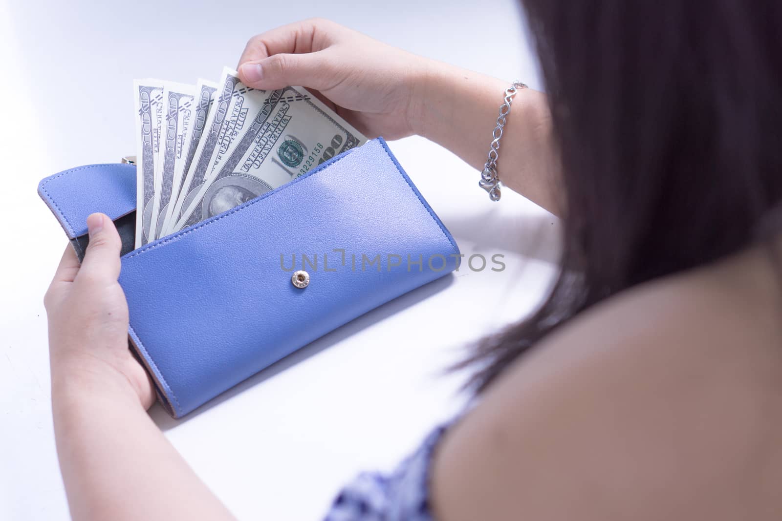 Woman hand taking out the money for payment from the blue wallet. Finance and money concept, copy space for text.