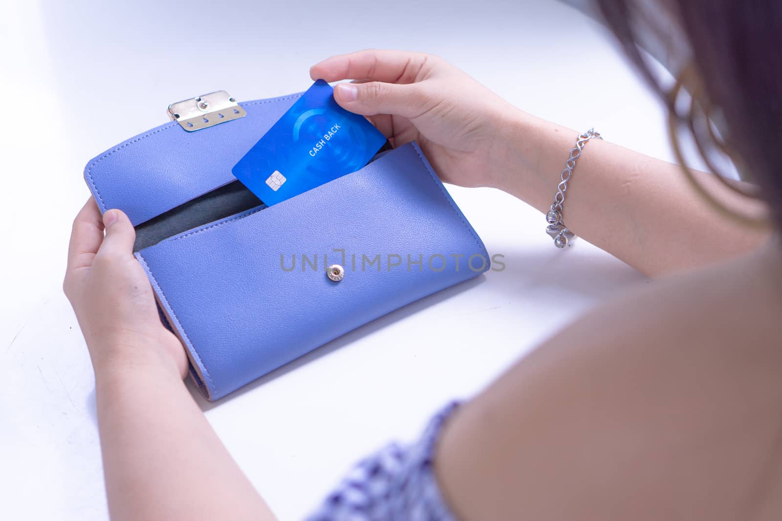 Woman hand taking out the credit card for payment from the blue wallet. Credit debit card with a chip.