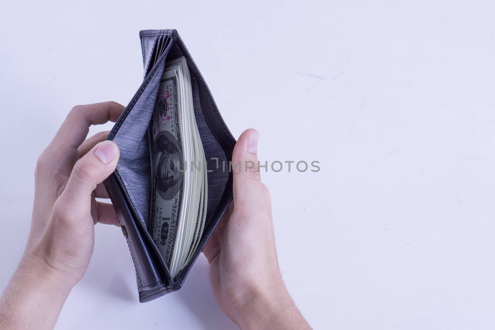 Rich man holding opened leather wallet full of dollar banknotes, by mikesaran