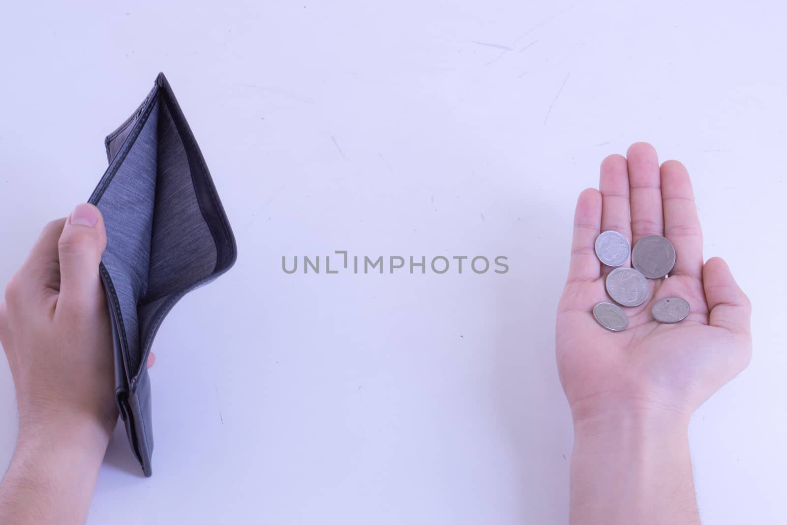 A man holds an empty wallet and coins in his hands on a white background. Finance problem and bankruptcy concept.