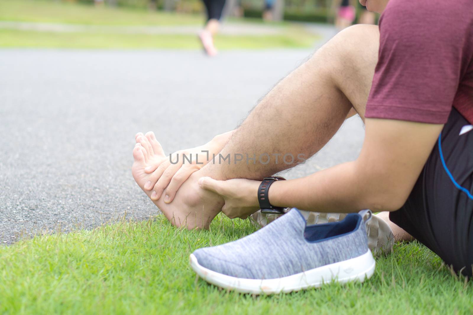 Ankle sprained. Young man suffering from an ankle injury while running at park. Healthcare and sport concept.