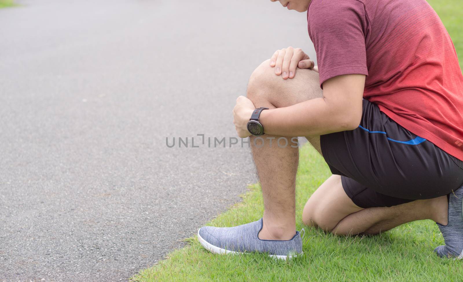 Knee Injuries. Young sport man holding knee with his hands in pain after suffering muscle injury during a running workout at park. Healthcare and sport concept.