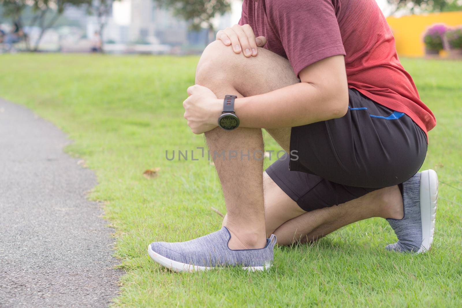 Knee Injuries. Young sport man holding knee with his hands in pain after suffering muscle injury during a running workout at park. Healthcare and sport concept.