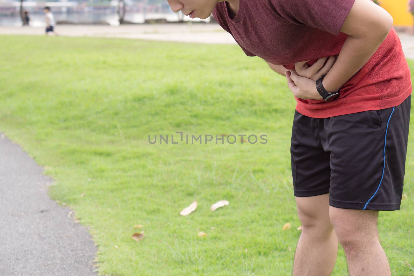 Sport man holding abdomen with his hands in stomach pain after running workout at park. Health care concept