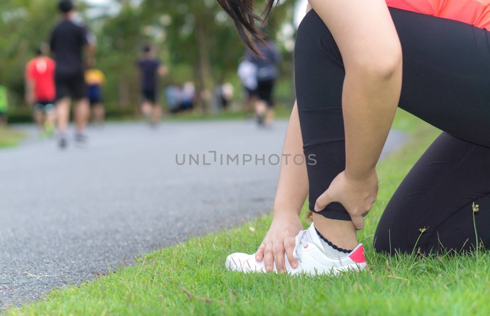 Ankle sprained. Young woman suffering from an ankle injury while jogging and running at the park. Healthcare and sport concept.