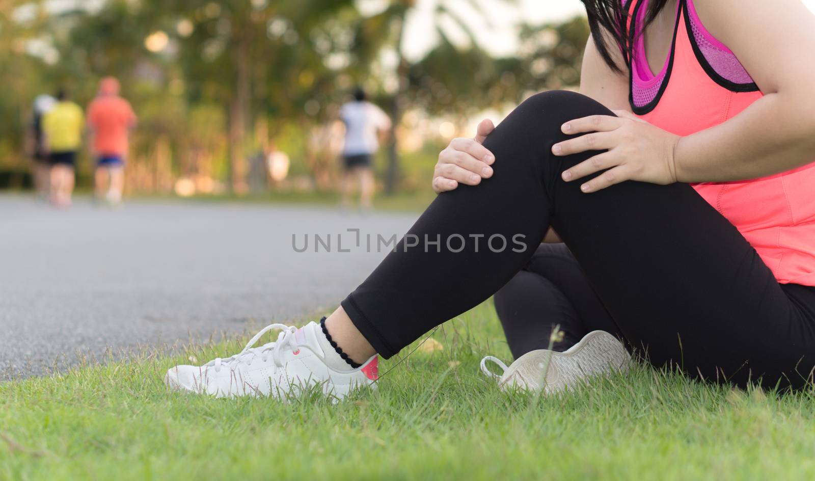 Knee Injuries. Young sport woman holding knee with her hands in pain after suffering muscle injury during a running workout at the park. Healthcare and sport concept.