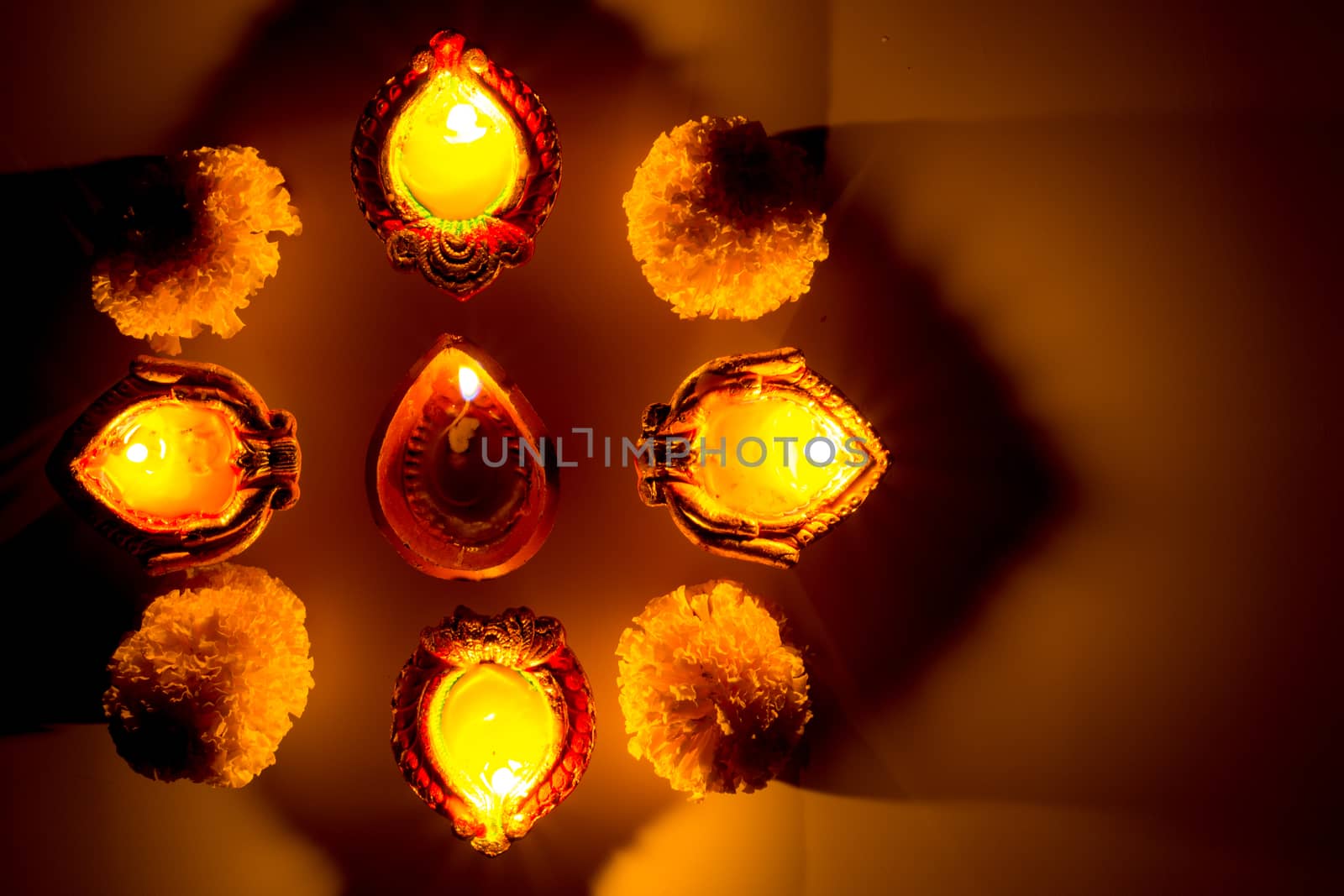 Indian festival Diwali, Diya oil lamps lit on colorful rangoli.  by mikesaran