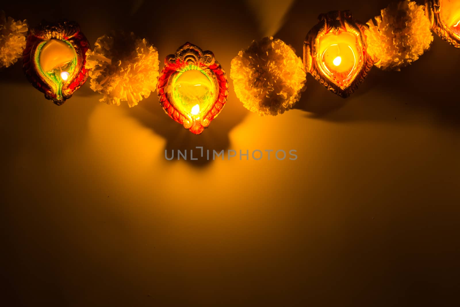 Indian festival Diwali, Diya oil lamps lit on colorful rangoli.  by mikesaran