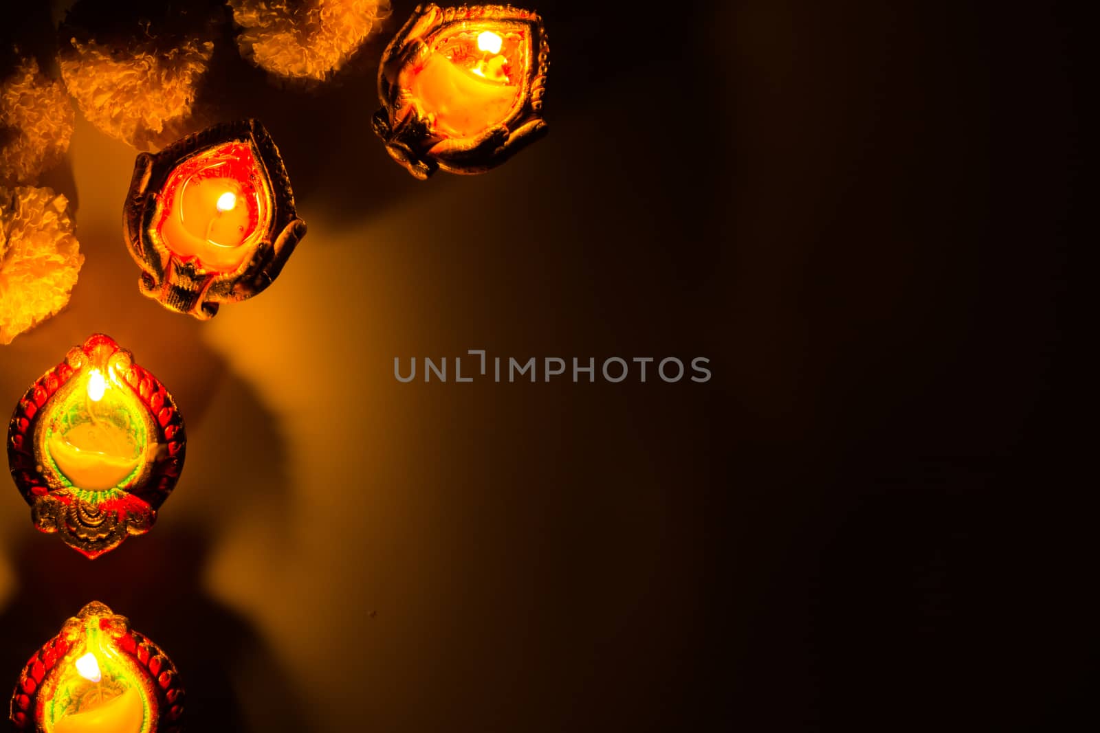 Indian festival Diwali, Diya oil lamps lit on colorful rangoli.  by mikesaran