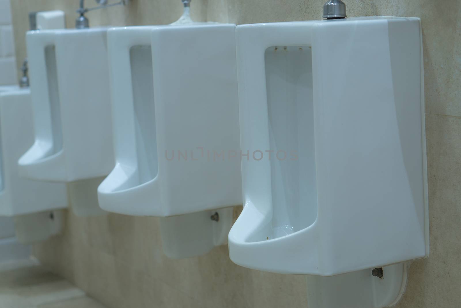 Men's room with white porcelain urinals in line. Comfort male toilet urinal concept.