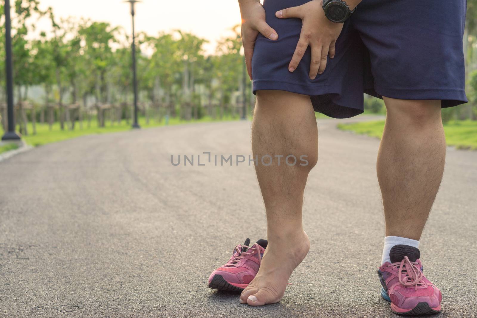 Knee Injuries. Fat man holding knee with his hands in pain after suffering muscle injury during a running workout at park. Healthcare and sport concept.