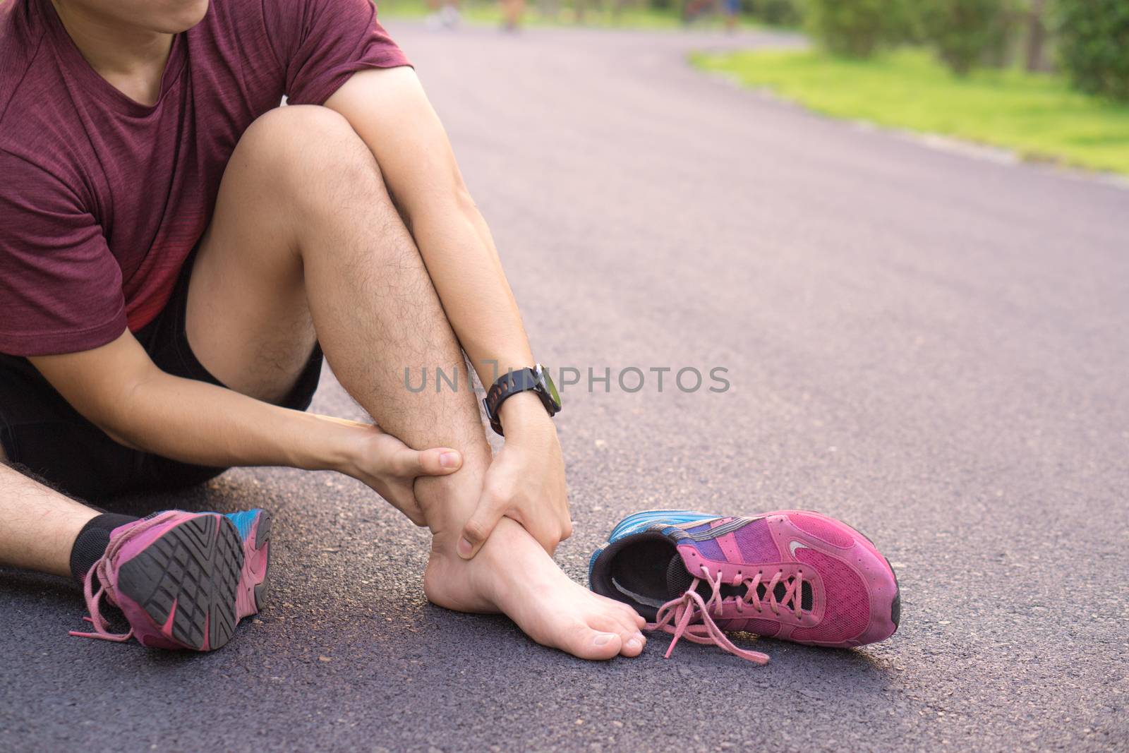 Ankle sprained. Young man suffering from an ankle injury while running at park. Healthcare and sport concept.