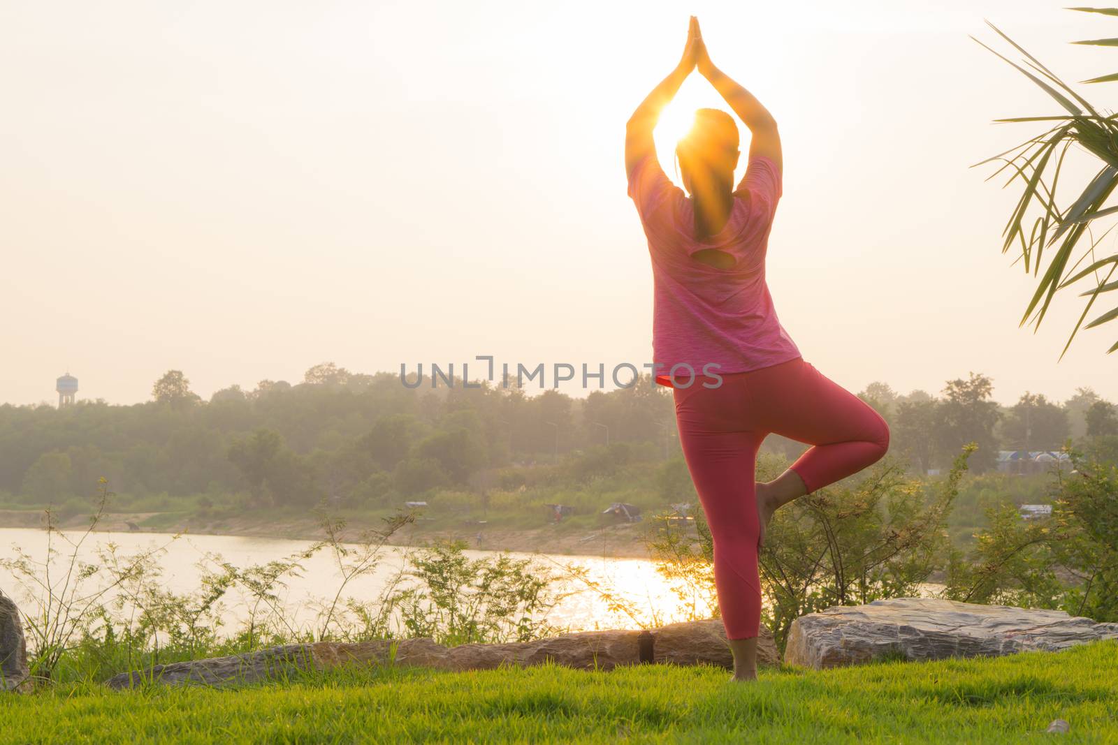 Asian woman practicing yoga in a garden. Healthy lifestyle and relaxation concept