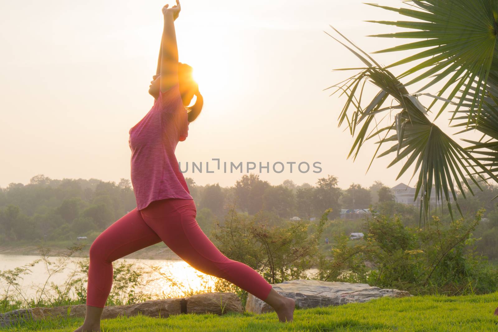 Asian woman practicing yoga in a garden. Healthy lifestyle and relaxation concept